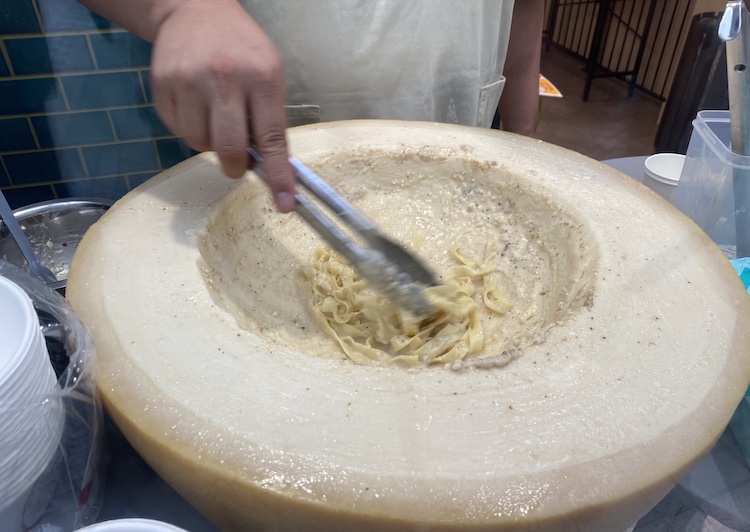 大きなチーズの中央にくぼみがあり、パスタを入れて混ぜている